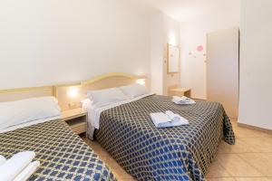 twee bedden in een hotelkamer met handdoeken erop bij Residenza Melucci in Rimini