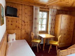 a bedroom with a bed and a table and a window at Der Waidachhof Zillertal in Hainzenberg