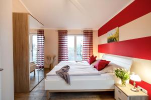 Un dormitorio con una cama blanca con una pared de acento rojo en Bauernhof Lafrenz en Fehmarn