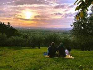 a group of three people sitting on a blanket in a field at Villa Clara in Assisi