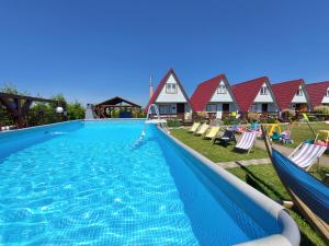a large swimming pool with two hammocks and some houses at Domki Letniskowe Słońce in Gąski