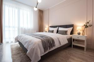 une chambre blanche avec un grand lit et une fenêtre dans l'établissement Snowdrop Apartment, à Sinaia