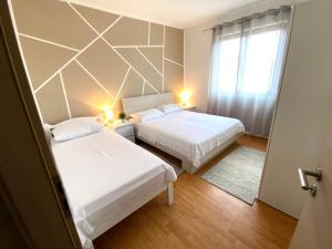 2 Betten in einem kleinen Zimmer mit Fenster in der Unterkunft Apartment Marcella 1 in Ljubač