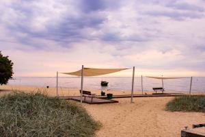 a beach with two picnic tables and a boat in the water at Luxus Apartament Wzgorze in Gdynia