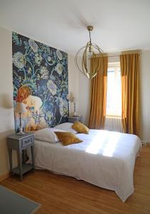 a bedroom with a large bed with a painting on the wall at Maison d'hôtes La Bella Casa in Villette-dʼAnthon