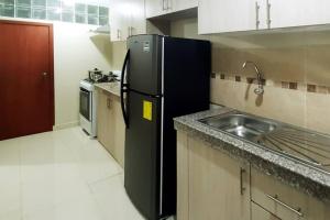 a kitchen with a black refrigerator and a sink at Chipipe Salinas Beachfront Apartment w Parking in Salinas