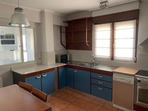 Una cocina con gabinetes azules y un fregadero. en Apartxibi, en Bermeo