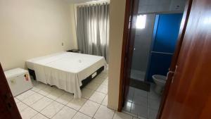 a small room with a bed and a toilet at Nacional Park Hotel Lages in Lages