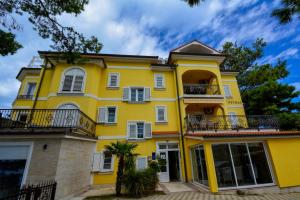 una casa gialla con finestre bianche e balconi di Apartment 10 in Villa Petrac a Rab