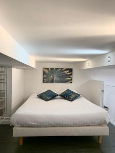 a bedroom with a white bed with two pillows at Studio Mezzanine Rue Pieta in Menton