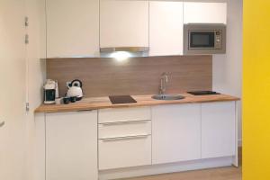 a kitchen with white cabinets and a sink and a microwave at B&B jaune, Appartement indépendant, parking, wifi près de Strasbourg in Ittenheim +4 photos