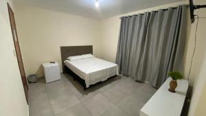 a small room with a bed and a curtain at Nacional Park Hotel Lages in Lages