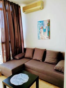 ein Wohnzimmer mit einem braunen Sofa und einem Tisch in der Unterkunft Sun City I Apart C27 in Sonnenstrand