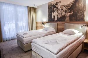 two beds in a hotel room with a picture on the wall at Strzelnica Hotel i Restauracja in Starogard Gdański