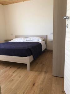 1 dormitorio con 1 cama y suelo de madera en Appartamenti la muraca en Capizzone