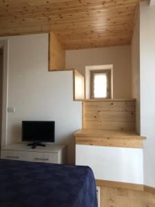 1 dormitorio con 1 cama y TV en la pared en Appartamenti la muraca en Capizzone