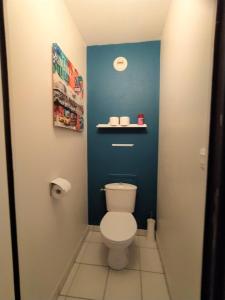 a bathroom with a toilet with a blue wall at Cocoon'Inn Blagnac in Blagnac