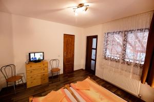 1 dormitorio con 1 cama, TV y ventana en Pensiunea Flori Sibiel en Sibiel