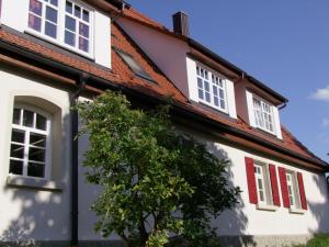 una casa bianca con finestre rosse e un albero di Stubersheimer Hof a Stubersheim