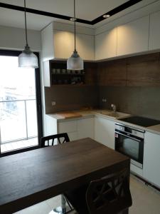 a kitchen with white cabinets and a wooden table at Apartament Zoom in Wrocław