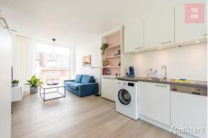 a kitchen with a washing machine and a blue couch at Lovely & Stylish accommodations at P36 Gent, near the Center in Ghent