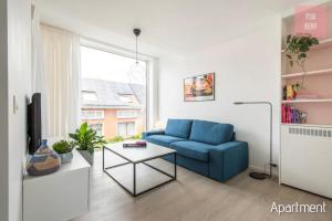 een woonkamer met een blauwe bank en een tafel bij Lovely & Stylish accommodations at P36 Gent, near the Center in Gent
