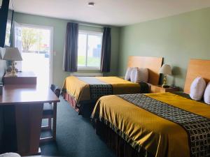 a hotel room with two beds and a window at Perth Plaza Inn & Suites in Perth