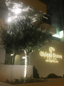 a tree in front of a building with a sign at Glyfada Riviera Hotel in Athens