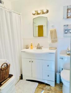 La salle de bains est pourvue d'un lavabo blanc et d'un miroir. dans l'établissement Across The INN Entire 3 bedrooms Colonial House with lovely porch and extremely fast Wi-Fi, à Washington, Virginia