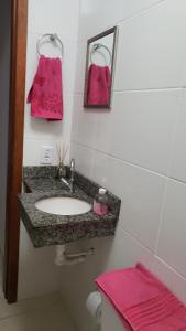 y baño con lavabo, espejo y toallas rosas. en Apartamento novo 450 mt da praia Ingleses, en Florianópolis