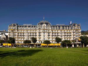 un grand bâtiment avec une pelouse devant lui dans l'établissement Fairmont Le Montreux Palace, à Montreux