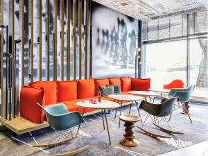 eine Lobby mit einem orangenen Sofa sowie Tischen und Stühlen in der Unterkunft ibis Hotel Hannover City in Hannover