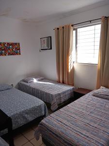 a hotel room with two beds and a window at Casa Rosarinho 1- RECIFE - Quartos com Banheiros Exclusivos in Recife