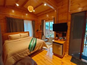 a bedroom with a bed and a flat screen tv at Soundless Resort in Khao Kho