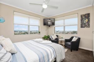 a bedroom with a bed and a tv and two chairs at Beach Haven on The Hill in Newcastle