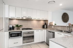 a kitchen with a stove a sink and a dishwasher at Grandview Apartments in Ballina