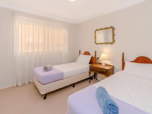 una camera da letto con due letti e uno specchio di Shellcot a Yamba