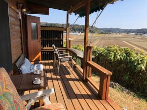 a porch with chairs and a table and an umbrella at 南房総 貸切コテージ セントシュバイン in Minamiboso