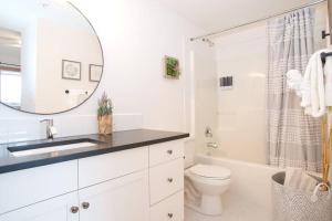 a bathroom with a sink and a toilet and a mirror at Pinnacle Mountain View Condo 3 Bed 2 Bath Downtown Canmore in Canmore