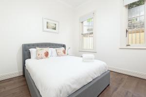 a white bedroom with a large bed with white sheets at STUNNING SYDNEY HOME 1 in Sydney