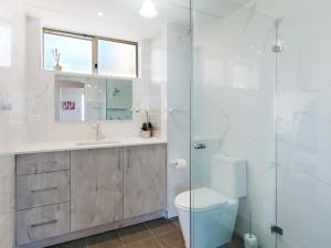 uma casa de banho com um WC e uma cabina de duche em vidro. em Blue Waters 6 em Shoal Bay