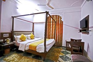 een slaapkamer met een hemelbed en een televisie bij Hotel Rang Sagar Haveli in Udaipur