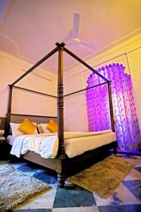 een slaapkamer met een hemelbed met paarse verlichting bij Hotel Rang Sagar Haveli in Udaipur