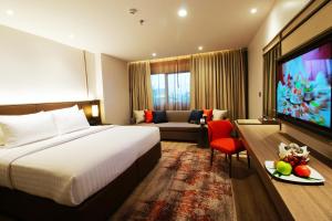 a hotel room with a bed and a couch and a television at Sima Thani Hotel in Nakhon Ratchasima