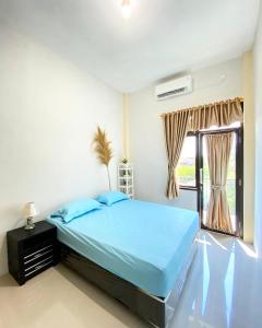 a bedroom with a blue bed and a window at Darma Palace Syariah in Padang