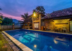 a villa with a swimming pool in front of a house at The Amrta Borobudur in Borobudur