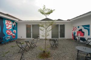 einen Innenhof mit Tischen, Stühlen und einem Baum in der Unterkunft Bobopod Dago, Bandung in Bandung