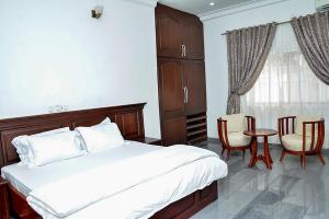 2 Bedroom Bungalow in Alalubosa GRA في إيبادان: غرفة نوم بسرير وطاولة وكراسي