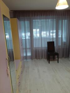 um quarto com uma cadeira e janelas grandes em Luny apartment em Ruse