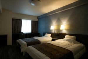 a hotel room with two beds and a window at Sakura Hotel Onomichi Ekimae in Onomichi